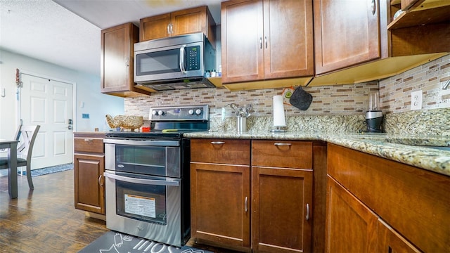 kitchen featuring decorative backsplash, stainless steel appliances, light stone counters, and dark hardwood / wood-style flooring