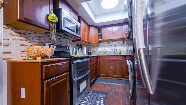 kitchen with appliances with stainless steel finishes, sink, tasteful backsplash, and dark hardwood / wood-style floors