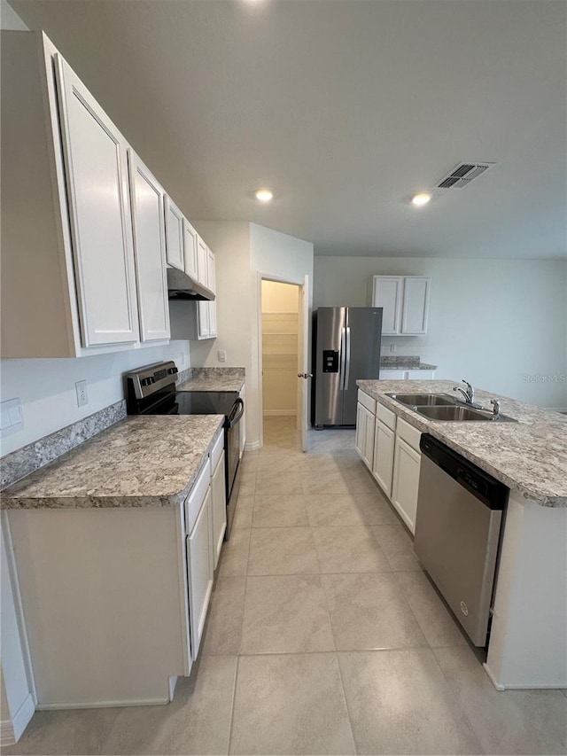 kitchen with white cabinetry, sink, light stone counters, appliances with stainless steel finishes, and light tile patterned floors