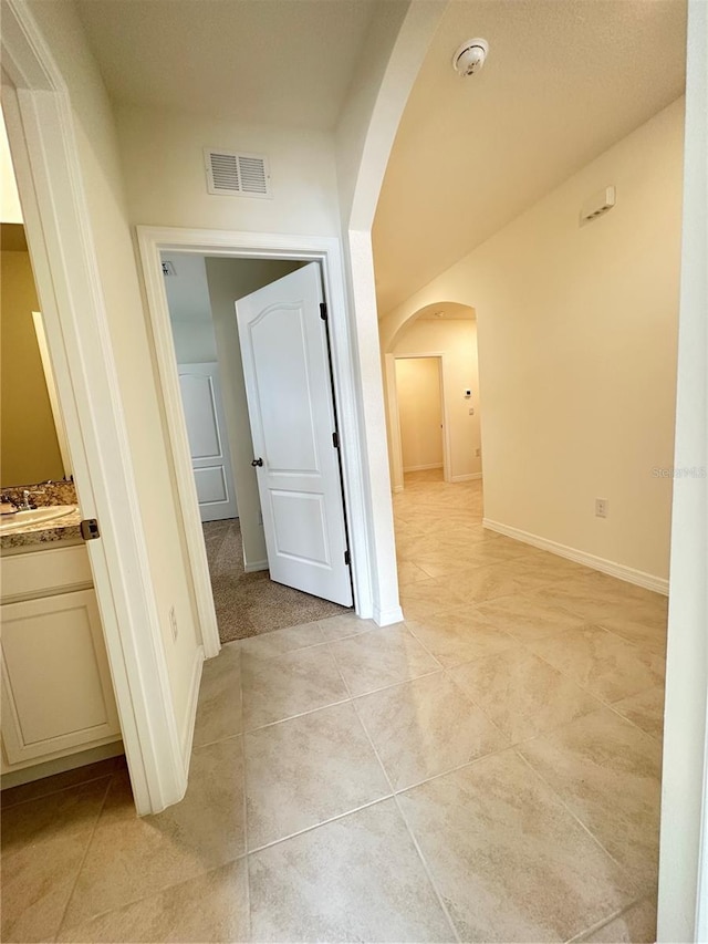 corridor with light tile patterned flooring and sink