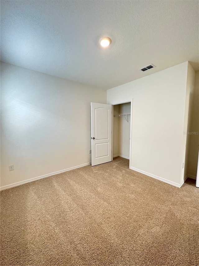 unfurnished bedroom with a closet, a textured ceiling, and carpet floors