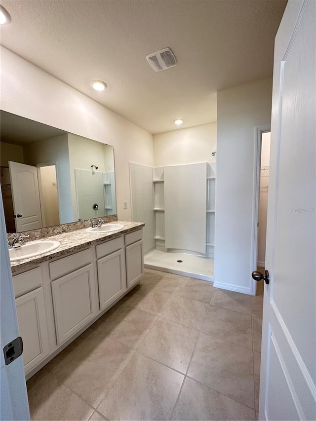 bathroom with vanity, walk in shower, a textured ceiling, and tile patterned floors