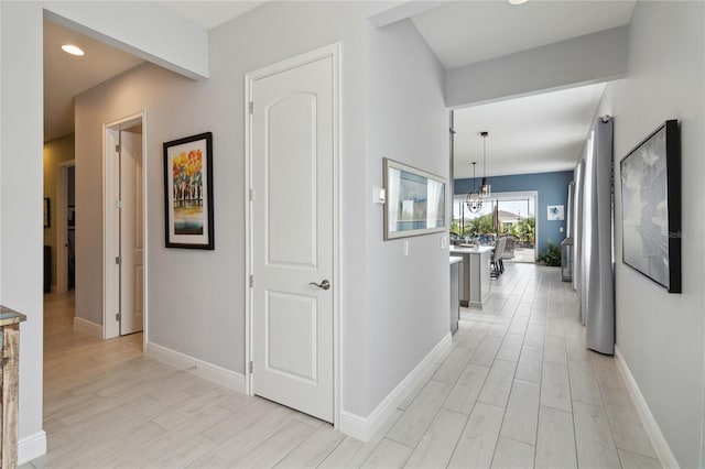 hall featuring light hardwood / wood-style floors and a chandelier