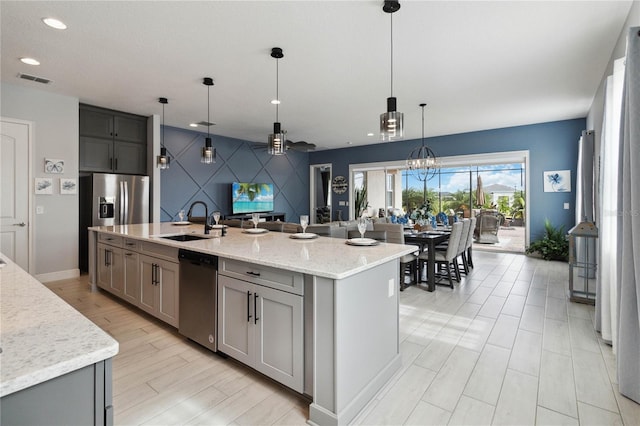 5075 Twin Lakes Blvd, Saint Cloud, FL 34772 - kitchen featuring stainless steel dishwasher, a sink, gray cabinetry, a center island with sink, and light stone countertops