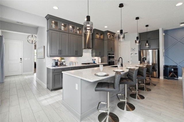 kitchen with decorative light fixtures, an island with sink, a breakfast bar, and stainless steel appliances