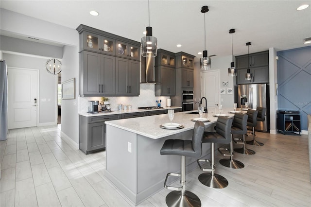 5075 Twin Lakes Blvd, Saint Cloud, FL 34772 - kitchen with appliances with stainless steel finishes, wall chimney exhaust hood, decorative backsplash, a kitchen bar, and a spacious island