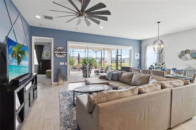 living room featuring ceiling fan with notable chandelier and light hardwood / wood-style floors