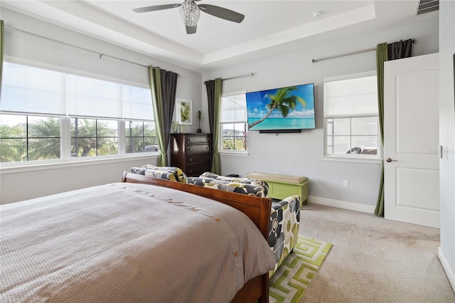 carpeted bedroom featuring ceiling fan and a tray ceiling