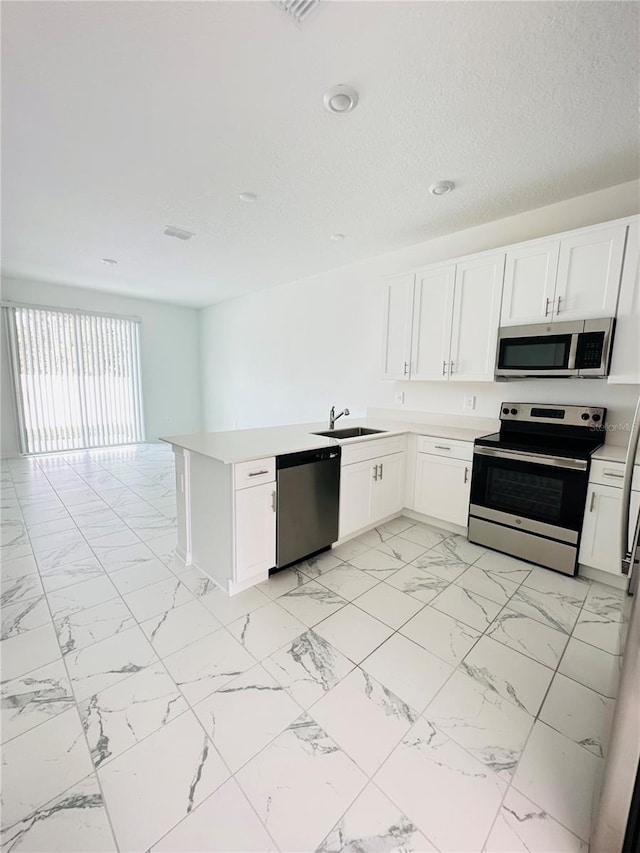 kitchen featuring stainless steel appliances, white cabinetry, sink, and kitchen peninsula