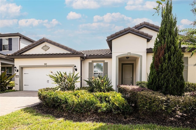 7845 Wandering Way, Orlando, FL 32836 - view of front of property featuring a garage, decorative driveway, a tiled roof, and stucco siding