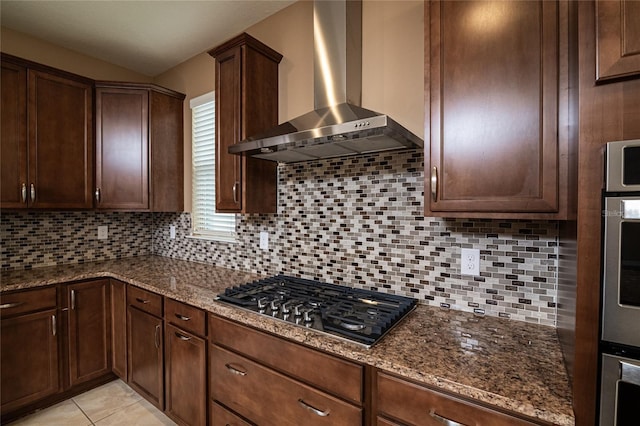 kitchen with oven, wall chimney range hood, backsplash, black gas cooktop, and dark stone countertops