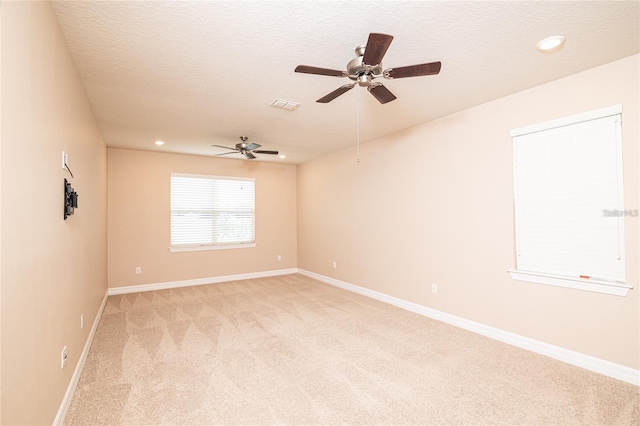 spare room featuring ceiling fan, a textured ceiling, and light carpet