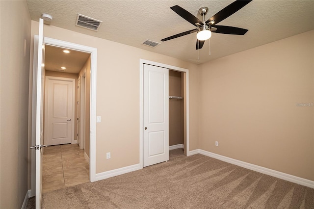 unfurnished bedroom featuring a textured ceiling, light carpet, ceiling fan, and a closet