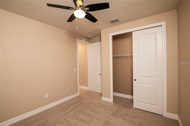 unfurnished bedroom featuring ceiling fan, a textured ceiling, a closet, and light colored carpet