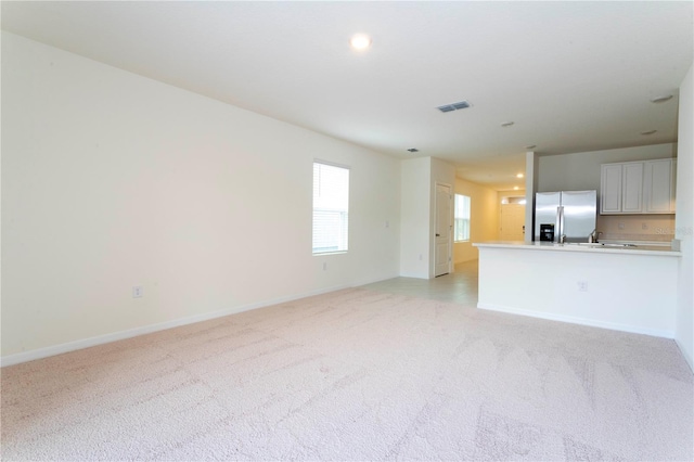 unfurnished living room with light colored carpet