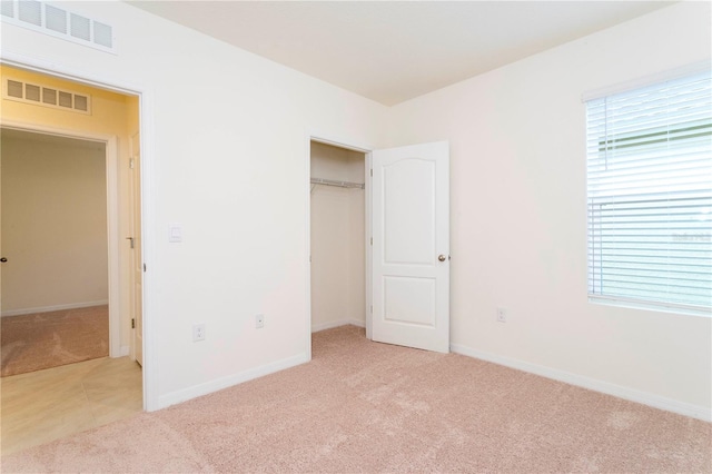 unfurnished bedroom with multiple windows, light carpet, and a closet