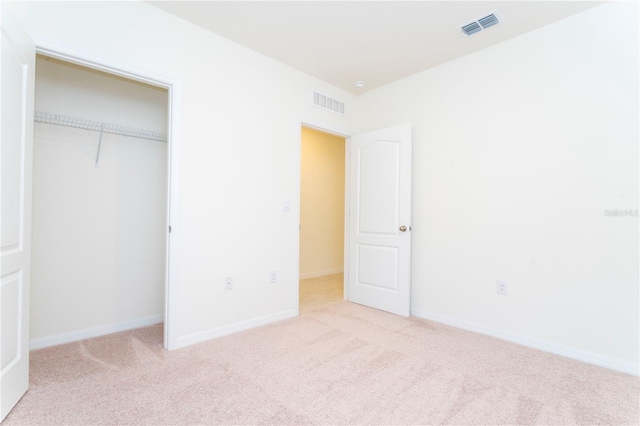 unfurnished bedroom featuring light carpet and a closet