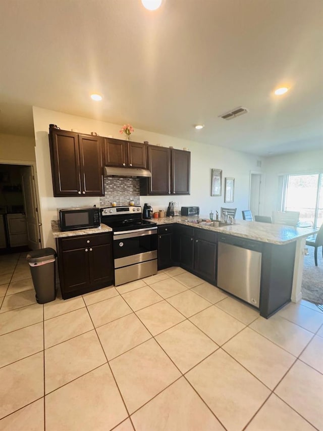 kitchen featuring kitchen peninsula, stainless steel appliances, light tile patterned floors, dark brown cabinets, and sink