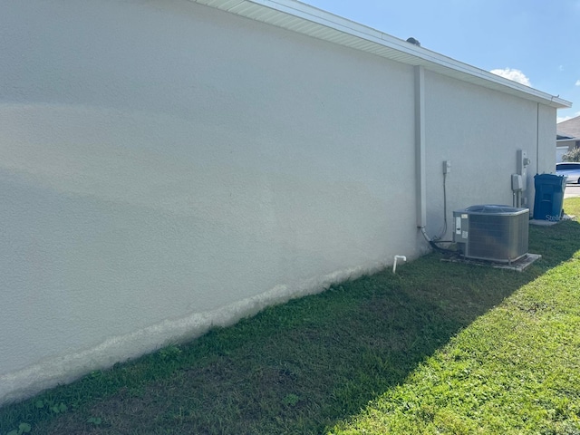 view of side of property featuring cooling unit and a yard