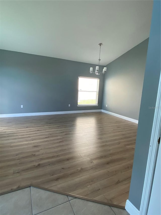 spare room with dark wood-type flooring and a chandelier