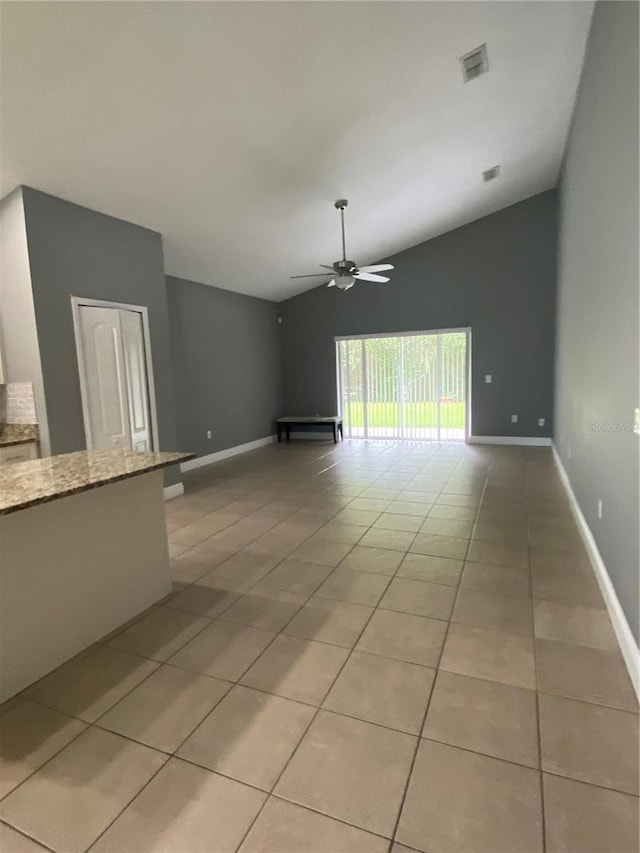 empty room with light tile patterned flooring, ceiling fan, and vaulted ceiling