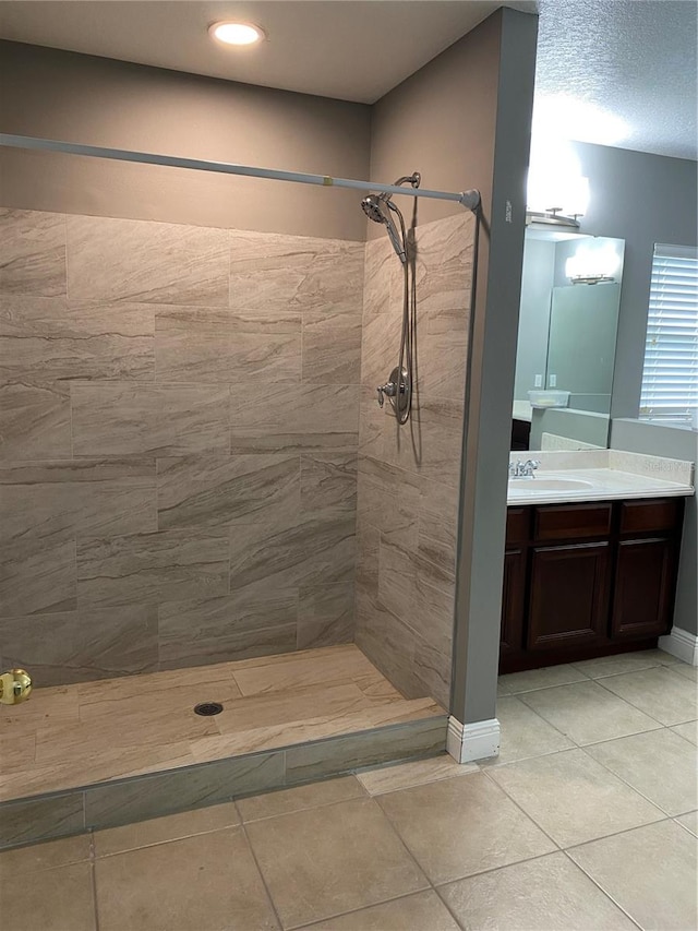 bathroom with vanity, tile patterned flooring, and a tile shower