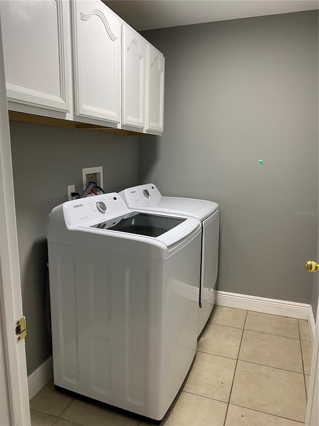 laundry area featuring light tile patterned floors, cabinets, and washing machine and clothes dryer