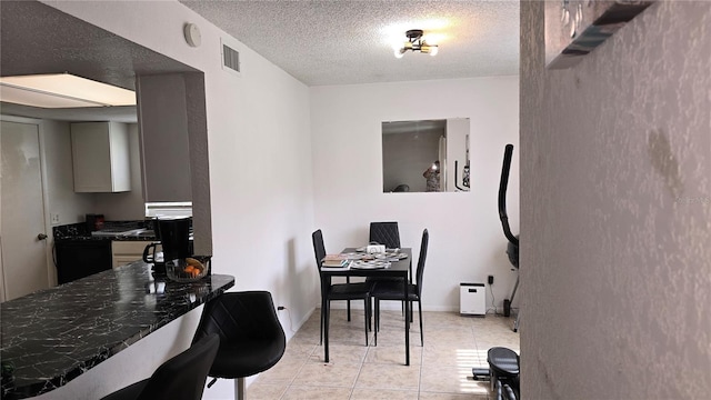 tiled dining space with a textured ceiling