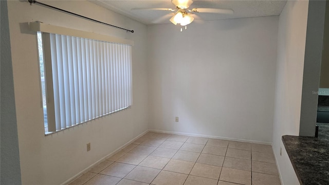 tiled empty room with ceiling fan and a healthy amount of sunlight