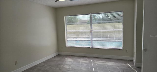 unfurnished room featuring ceiling fan, a healthy amount of sunlight, and a textured ceiling