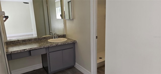 bathroom with hardwood / wood-style flooring, vanity, and a shower