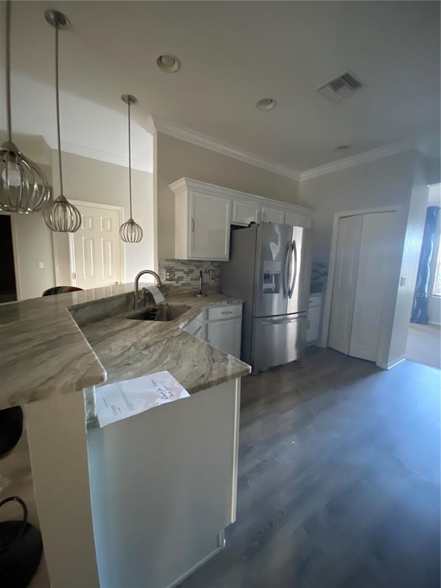 kitchen featuring sink, kitchen peninsula, white cabinets, stainless steel fridge, and pendant lighting