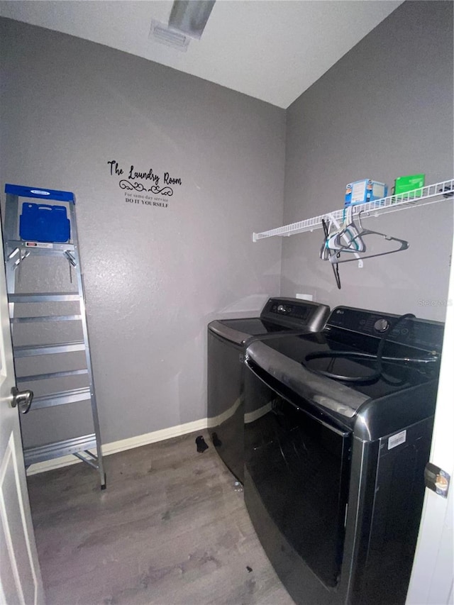 clothes washing area with hardwood / wood-style floors and washer and dryer