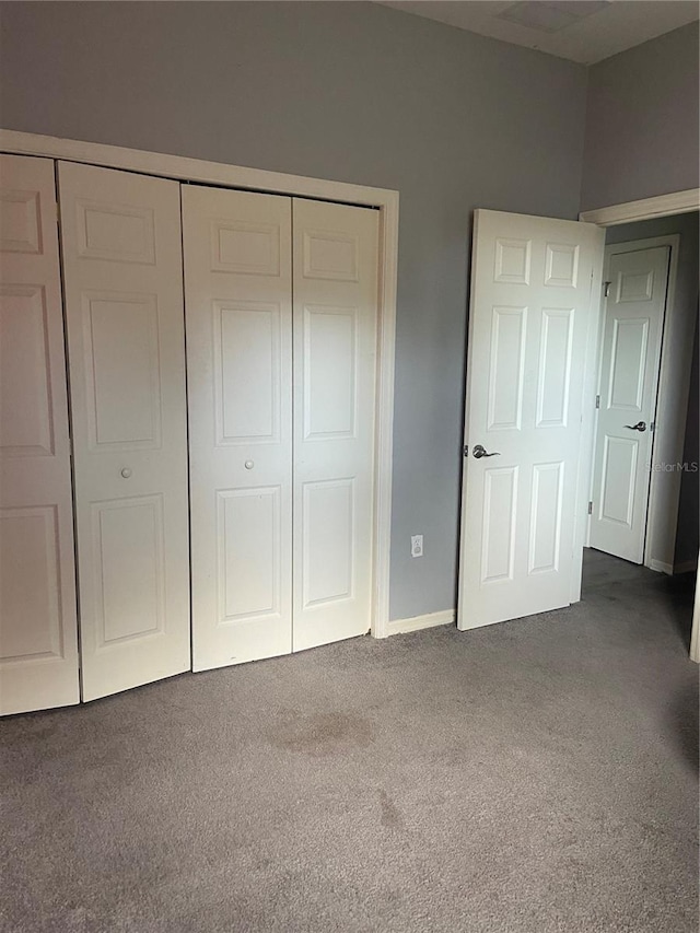 unfurnished bedroom with dark colored carpet and a closet