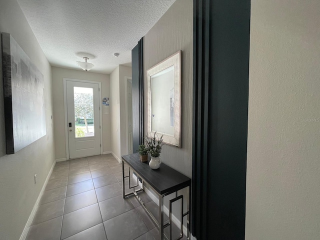 doorway to outside featuring dark tile patterned floors and a textured ceiling