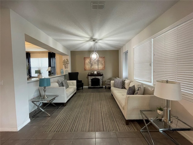 tiled living room with a stone fireplace and a textured ceiling