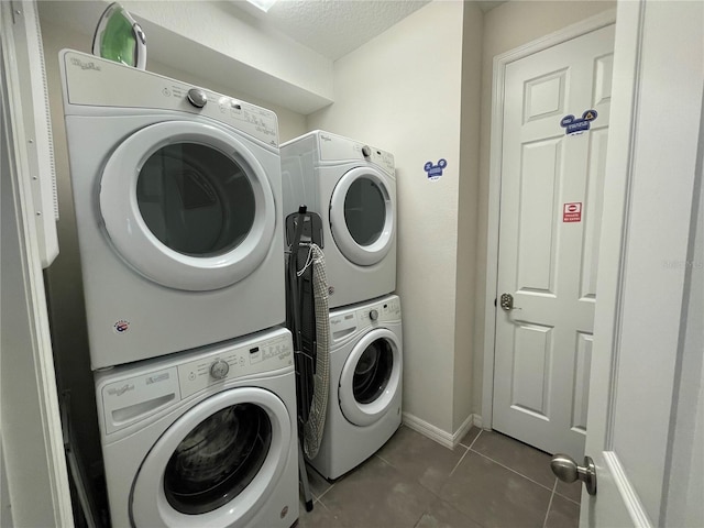 laundry room featuring stacked washer and dryer, a textured ceiling, and dark tile patterned floors