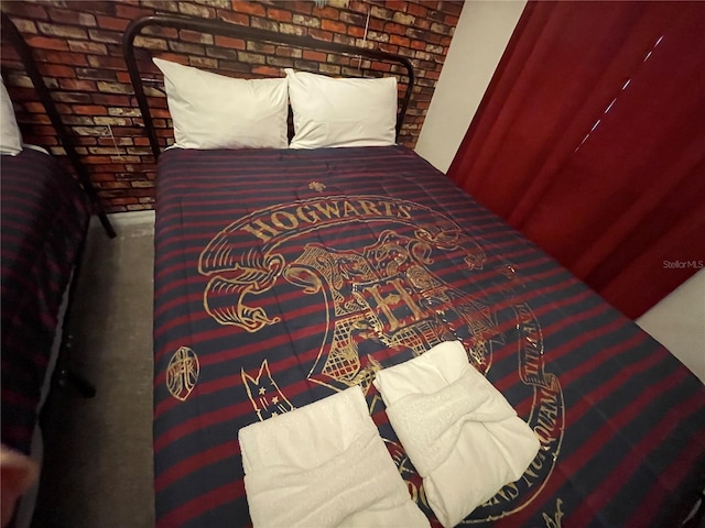 bedroom with carpet flooring and brick wall