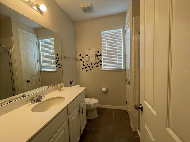 bathroom featuring toilet, vanity, tile patterned floors, and a shower with shower door