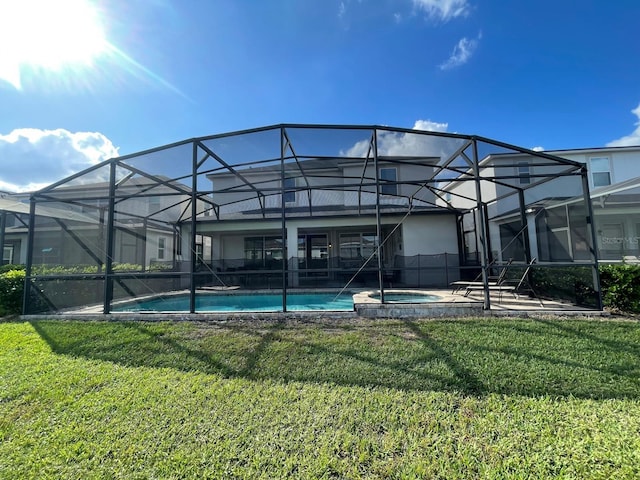 rear view of property with a lanai, a yard, and an in ground hot tub