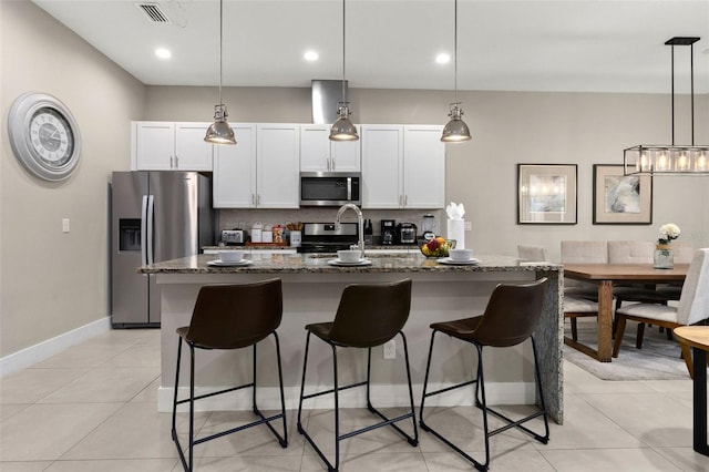 kitchen with sink, a kitchen island with sink, appliances with stainless steel finishes, and dark stone counters