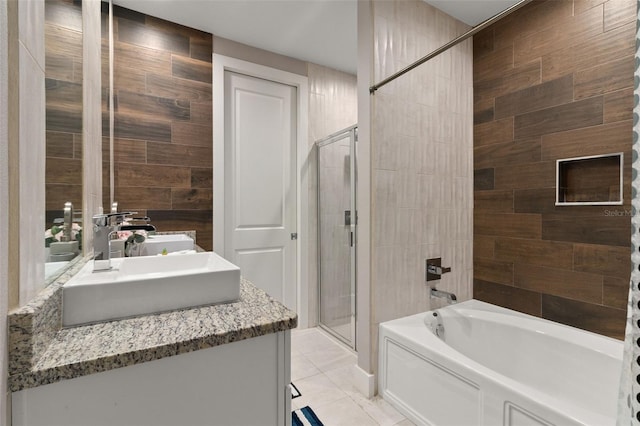 bathroom featuring tile patterned flooring, tiled shower / bath, vanity, and tile walls