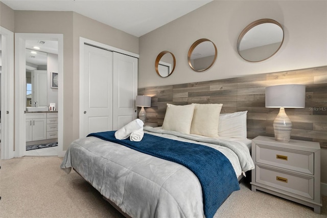 bedroom featuring light colored carpet, ensuite bath, a closet, and wood walls