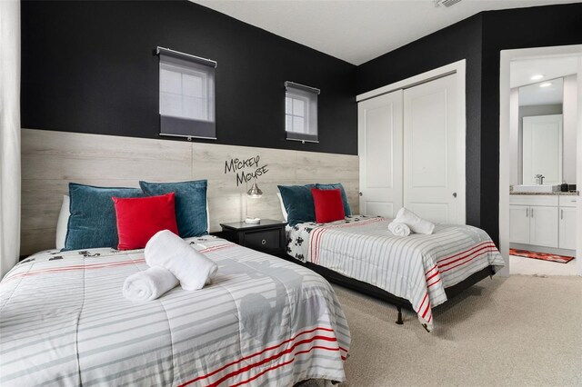 carpeted bedroom featuring ensuite bath, tile walls, and a closet