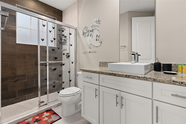 bathroom featuring tile patterned floors, a shower with door, vanity, and toilet