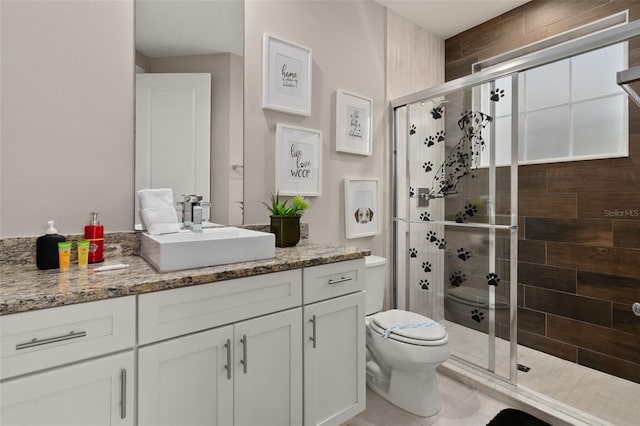 bathroom with tile patterned floors, a shower with door, vanity, and toilet