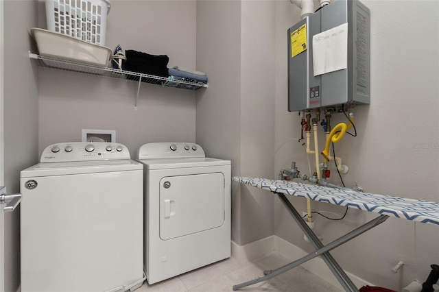 laundry area featuring tankless water heater, light tile patterned floors, and washing machine and clothes dryer