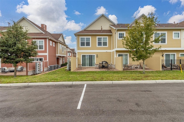 view of front of home with central AC unit, a front lawn, and a patio area