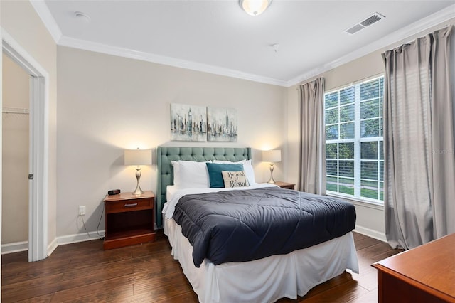 bedroom featuring a walk in closet, crown molding, a closet, and dark wood-type flooring