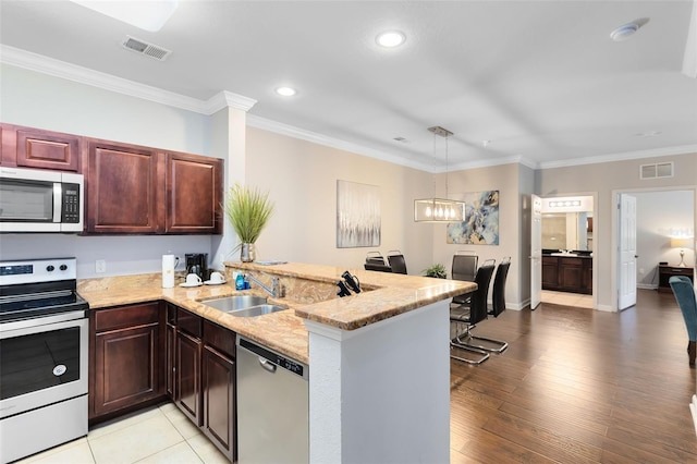 kitchen featuring light wood-type flooring, kitchen peninsula, stainless steel appliances, and a chandelier